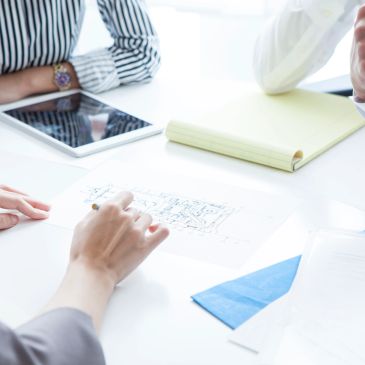 People discussing plans with documents and tablet on table.