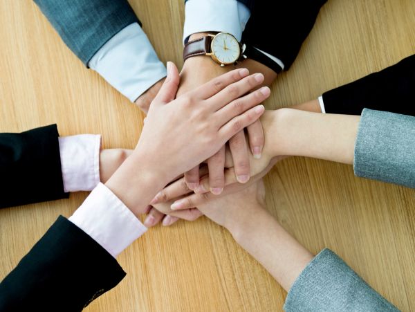 People stacking hands in a teamwork gesture.
