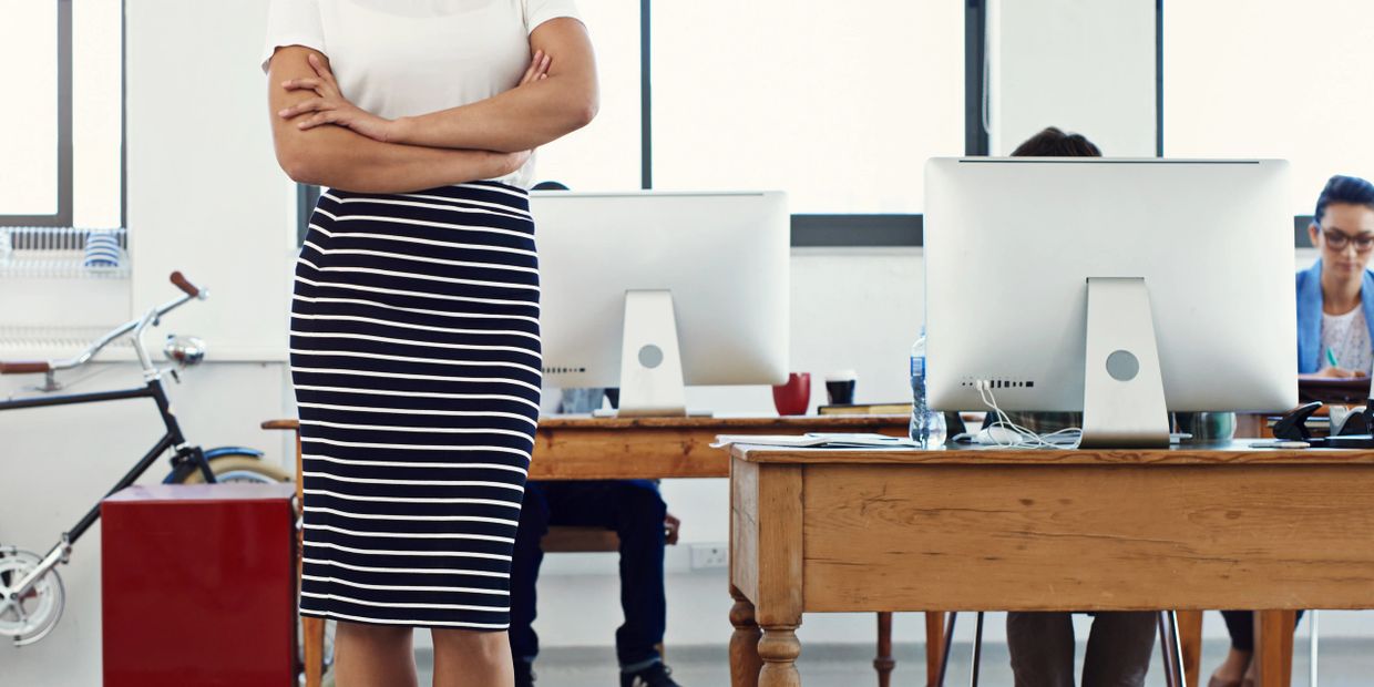 Confident woman standing with crossed arms in a modern office.