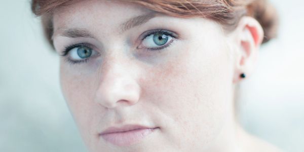 Close-up portrait of a woman with red hair and blue eyes.