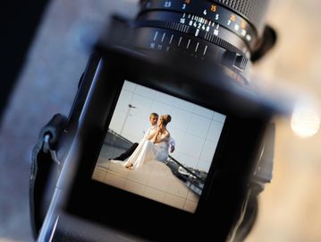 Bride and groom seen through a camera viewfinder during a photoshoot.