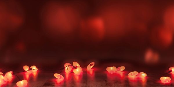 Glowing red heart-shaped lights on a wooden surface with a blurred red background.