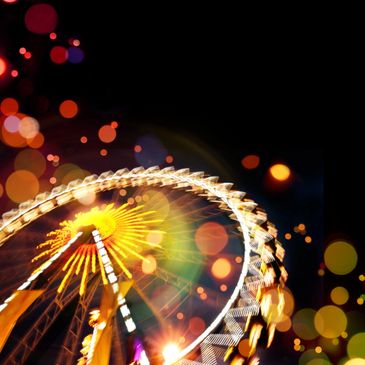 Blurred lit Ferris wheel at night with bokeh lights.