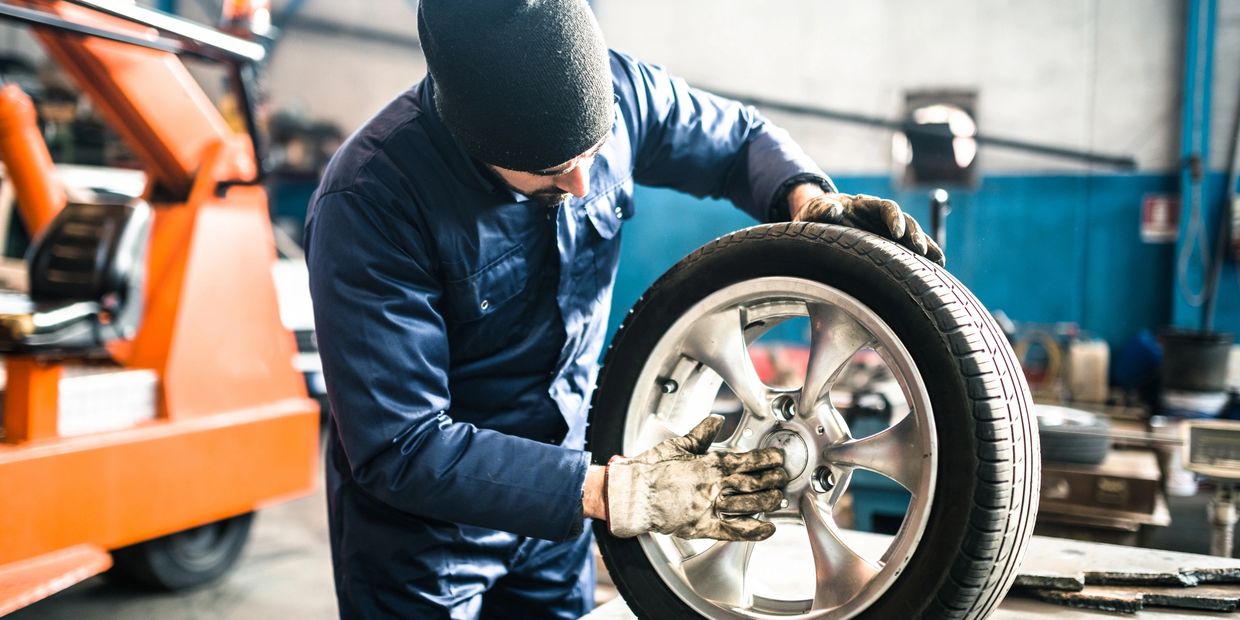 Mechanic inspecting a car tire in a workshop.