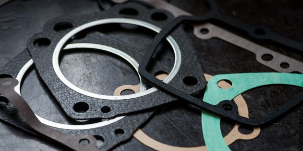 A variety of engine gaskets arranged on a dark surface.