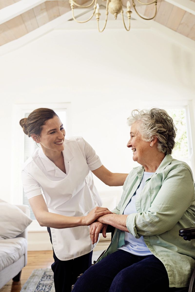Shot of a smiling caregiver helping a senior woman in a wheelchair at home