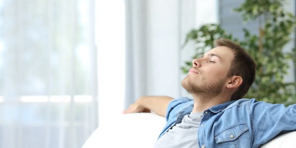 A man sitting on a couch taking a deep breath.