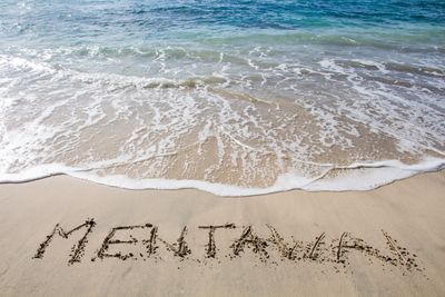 Mentawai Beach with the word Mentawai spelled out in the sand and a wave behind it.