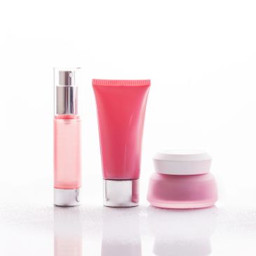 Three pink cosmetic containers on a white background.