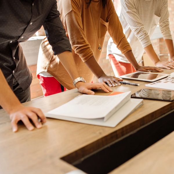A group collaborating over documents and tablets in a modern workspace.