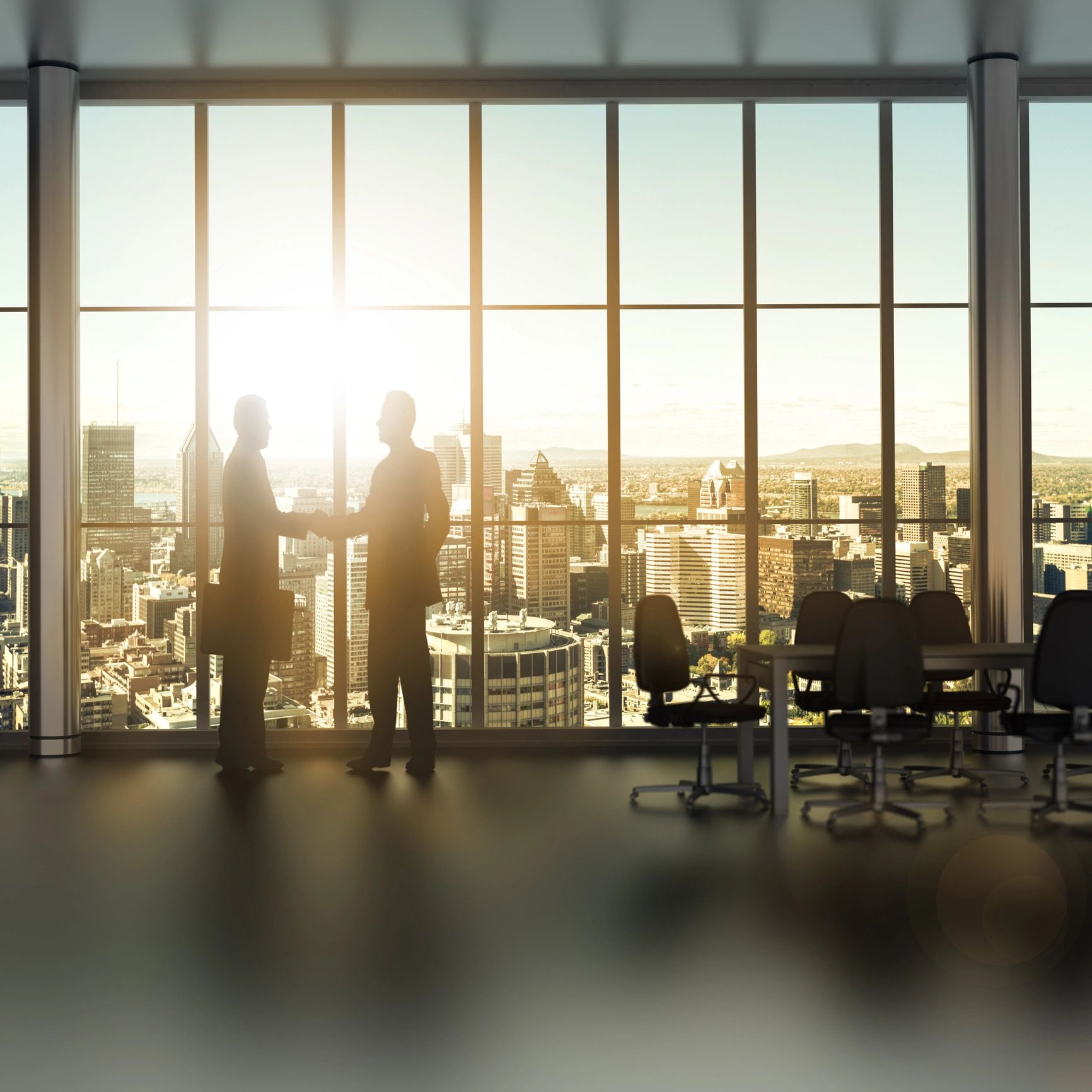 Two businessmen shaking hands in a high-rise office with a city view at sunset.