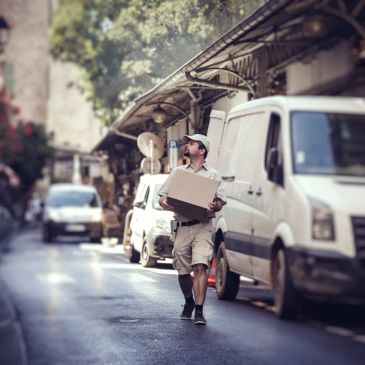 Delivery man walking with a package on a city street.