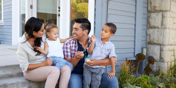 Happy family of four sitting on their front porch together.