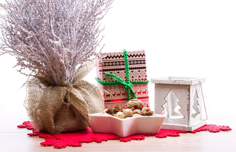 Christmas background with snow covered tree, candle holder, xmas present and star shaped bowl full of nuts, with copyspace