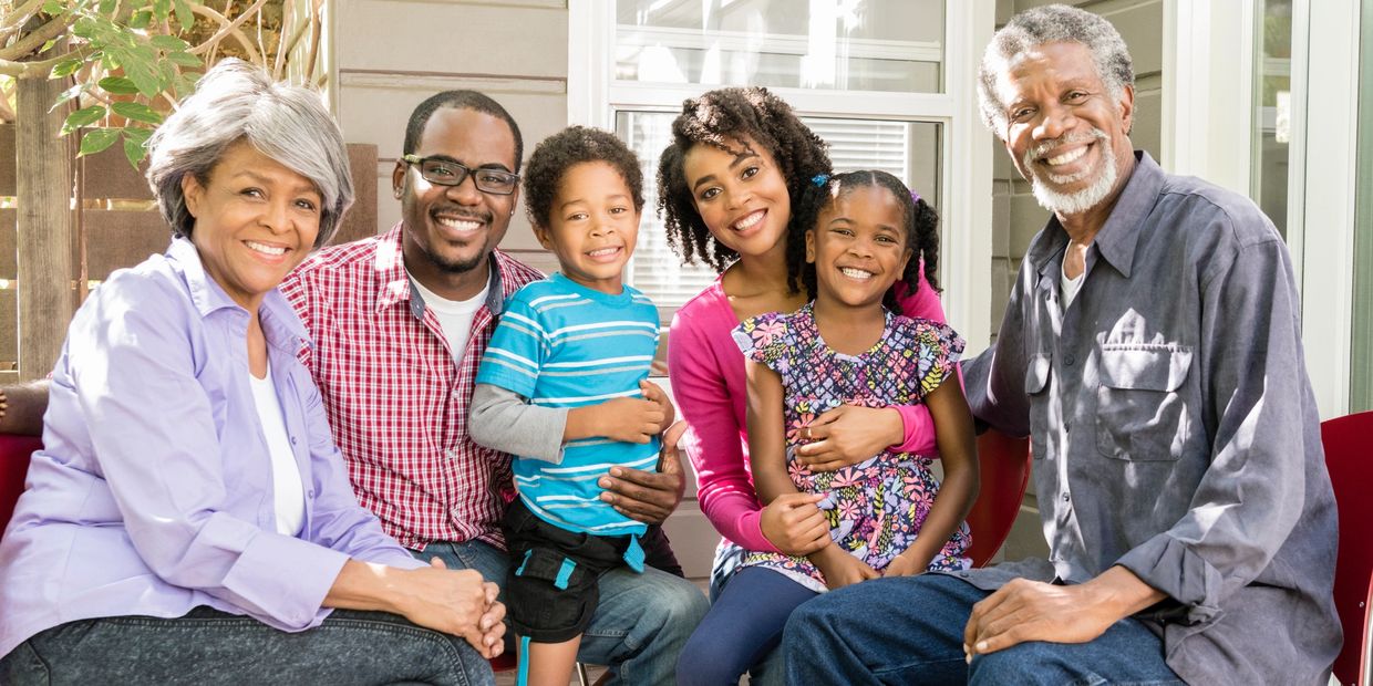 A happy multi-generational family posing together on a sunny day.
