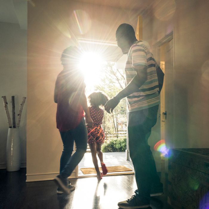 A family joyfully enters their home with sunlight streaming through the open door.