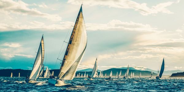 Sailboats racing on the water under a cloudy sky.