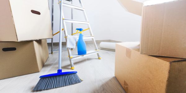 Broom and cleaning items beside moving boxes and ladder.