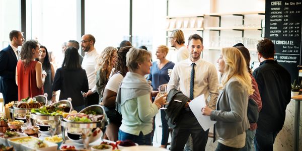 People socializing at a professional networking event with buffet food.