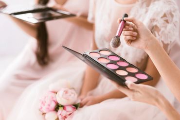Women applying pink makeup with a brush and palette.