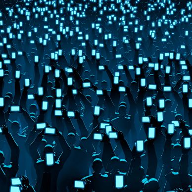 Crowd holding up glowing smartphones in a dark setting.