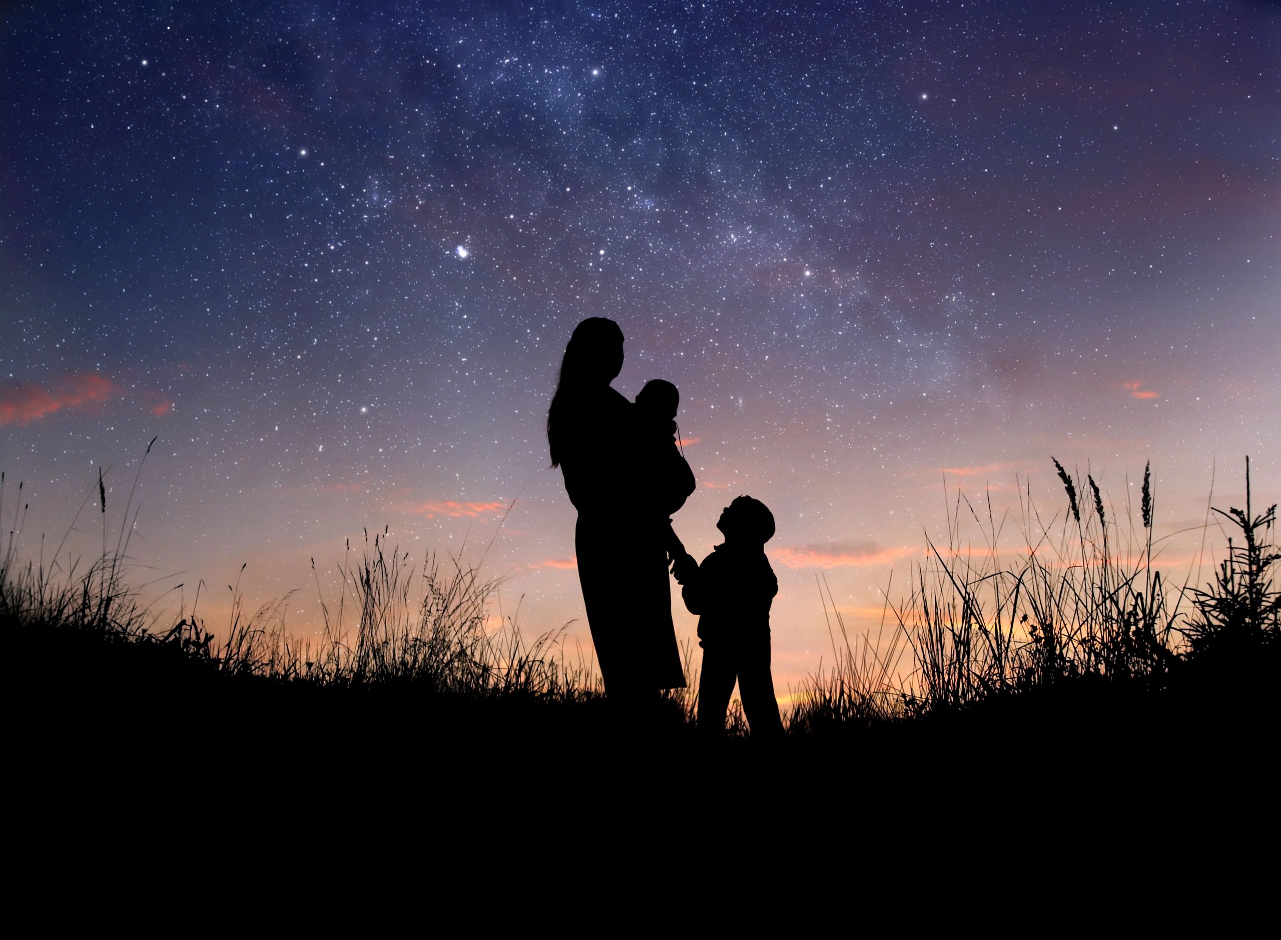 Silhouettes of a mother and two children under a starry twilight sky.
