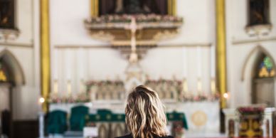 A woman praying inside a beautifully decorated church.