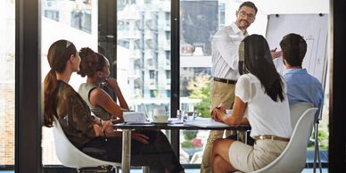 Business meeting with a presenter explaining data on a flip chart.