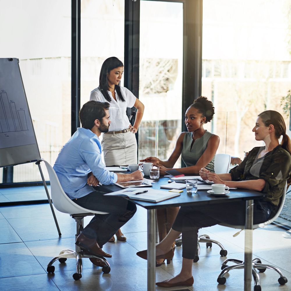 Four colleagues engaged in a discussion in a modern office.