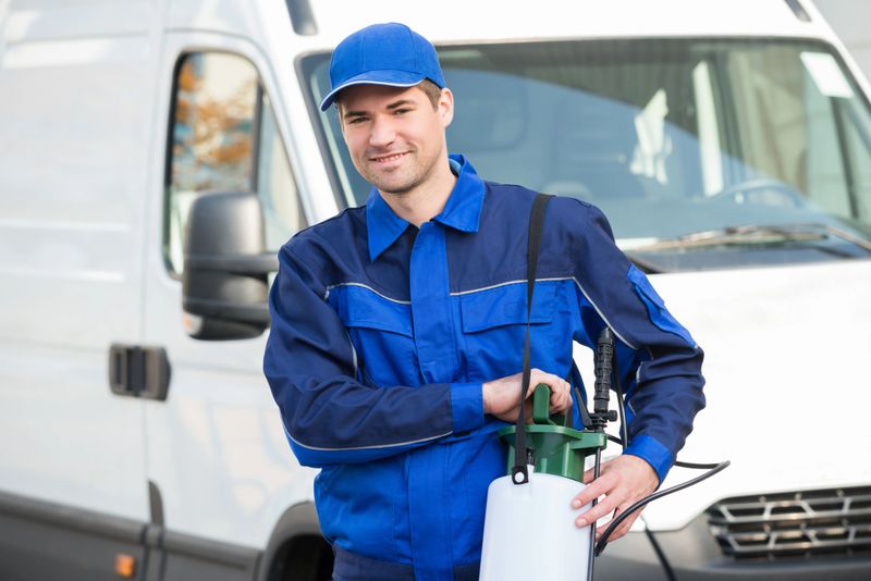 Portrait of confident pest control worker with pesticide against truck
