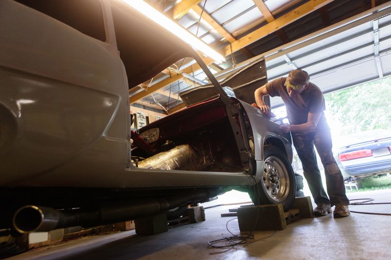 mechanic working in garage shop on antique car