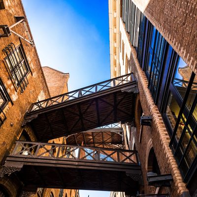 Two wooden pedestrian bridges connect brick buildings under a clear blue sky.