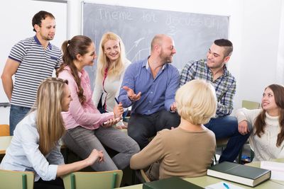 Group of young adults engaged in a lively discussion in a classroom.