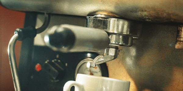 Close-up of espresso machine brewing coffee into white cup.