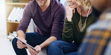 People sitting and smiling while looking at a tablet.