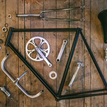 A bicycle frame and components individually layed out on a floor