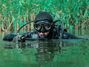 A man is scuba diving through a lake.