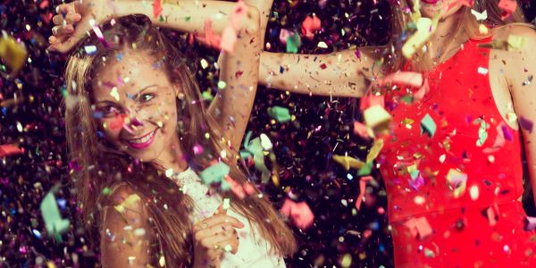 Two women joyfully celebrating with colorful confetti falling around them.