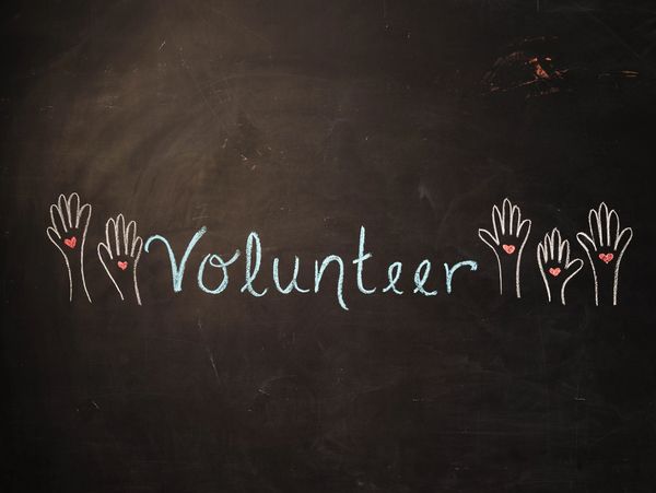 Chalk drawing of raised hands with hearts and the word 'Volunteer' on a blackboard.