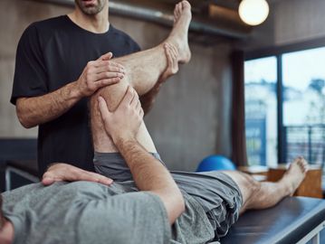 Physical therapist stretching a patient's leg during rehabilitation.