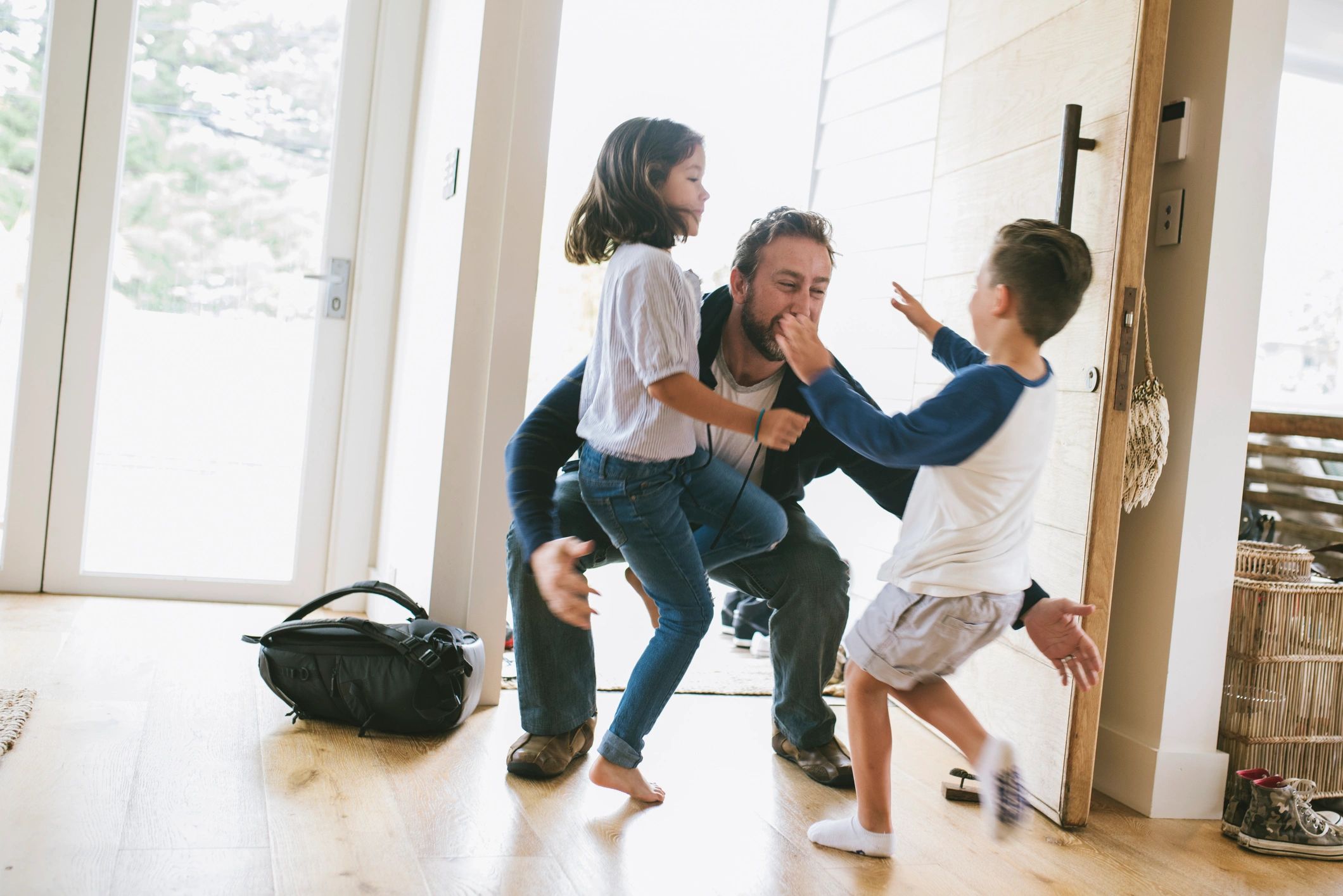 Children happily greet their father at home.