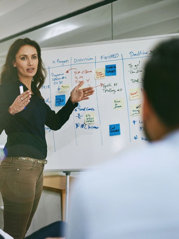 Woman explaining data on a whiteboard in a meeting.
