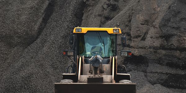 Front view of a yellow construction loader against a gravel background.