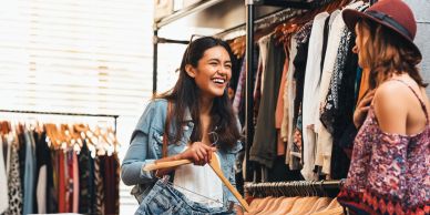 Two women shopping and smiling in a clothing store.