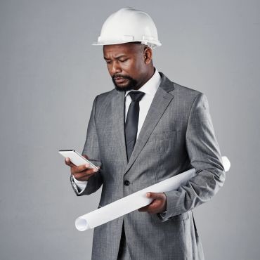 Architect or engineer in a suit and hard hat using a phone.