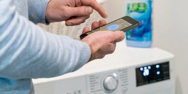 Person controlling a washing machine via smartphone app.