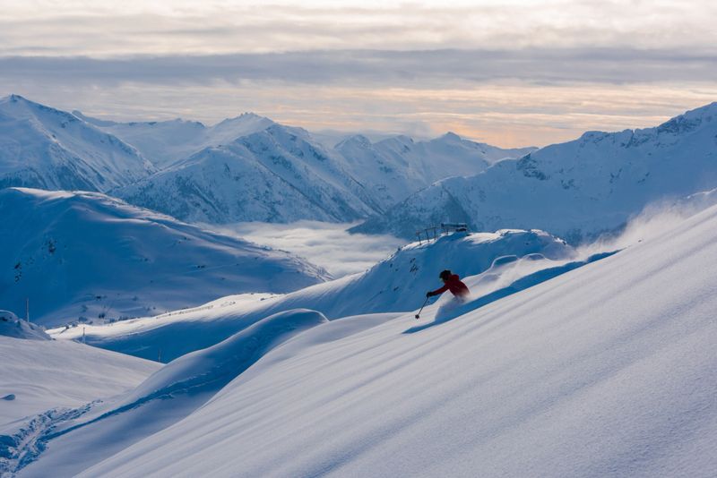 Female skier making a turn in pristine untouched fresh powder on a bluebird day enjoying the freedom, adventure and excitement of skiing in the mountains.  Skiing is a great way to get away from it all allowing you to live in the moment while experiencing nature at its finest.