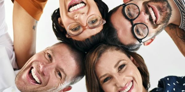 Four friends smiling in a close circle, looking down at the camera.