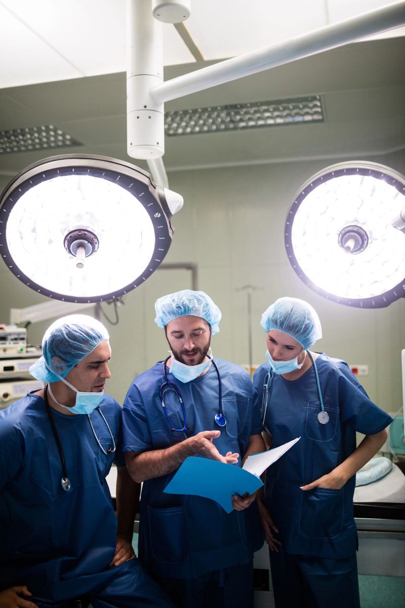 Surgeons discussing patient records in operation room at hospital