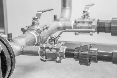 Close-up of industrial metal pipes and valves in a monochrome setting.